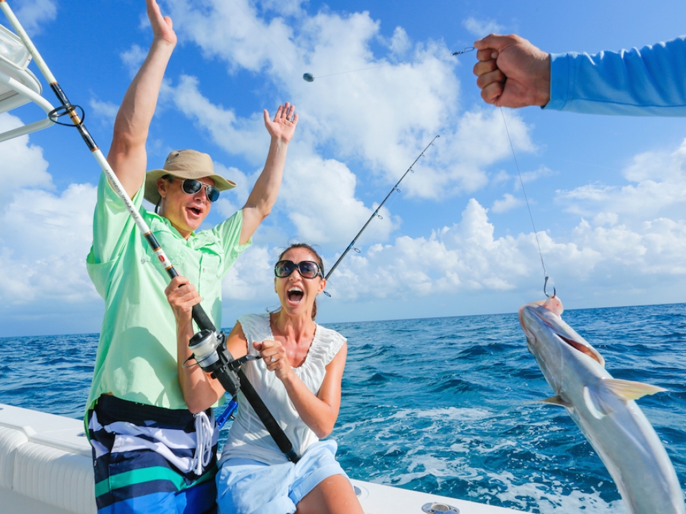 A man and woman reel in a fish on a boat trip in The Bahamas