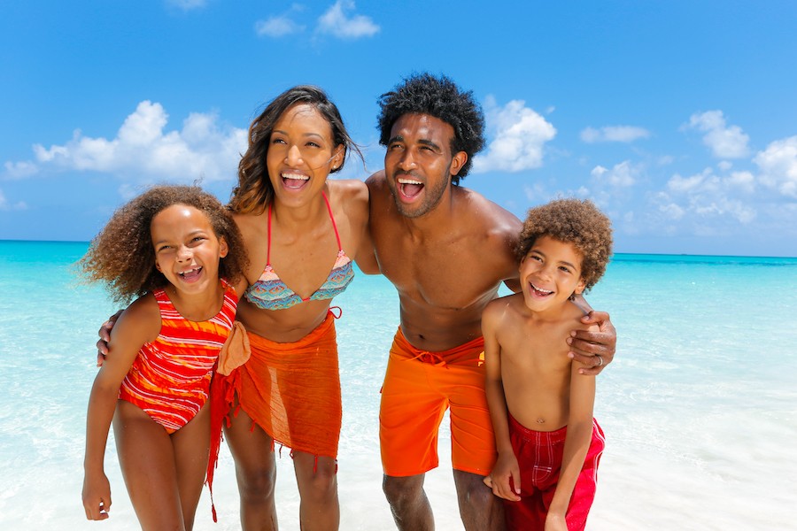 A family of four poses for a photo on the beach in Nassau Paradise Island. 