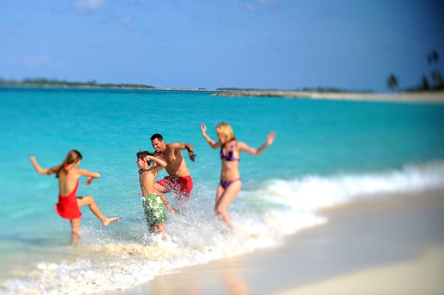 A family of four splashes in the turquoise waters of Nassau Paradise Island, Bahamas