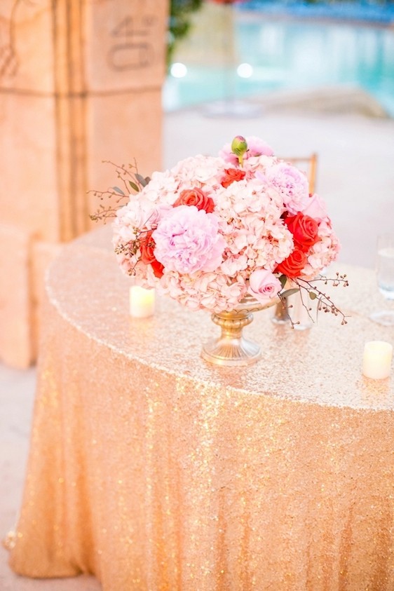 A pink floral bouquet sits on a beautiful gold tablecloth at an Atlantis wedding. 