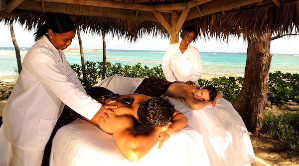 A man and woman enjoy a couples massage on the beach in The Bahamas. 