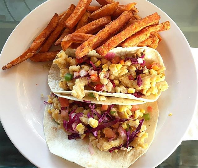 Shrimp tacos with sweet potato fries on a white plate.