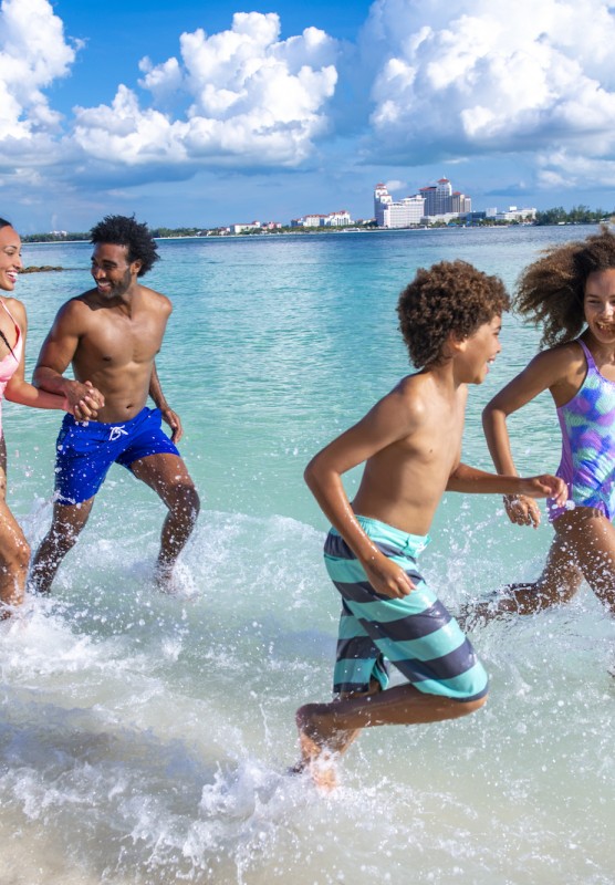 A family of fun splashes in the waves on a Bahamas beach.