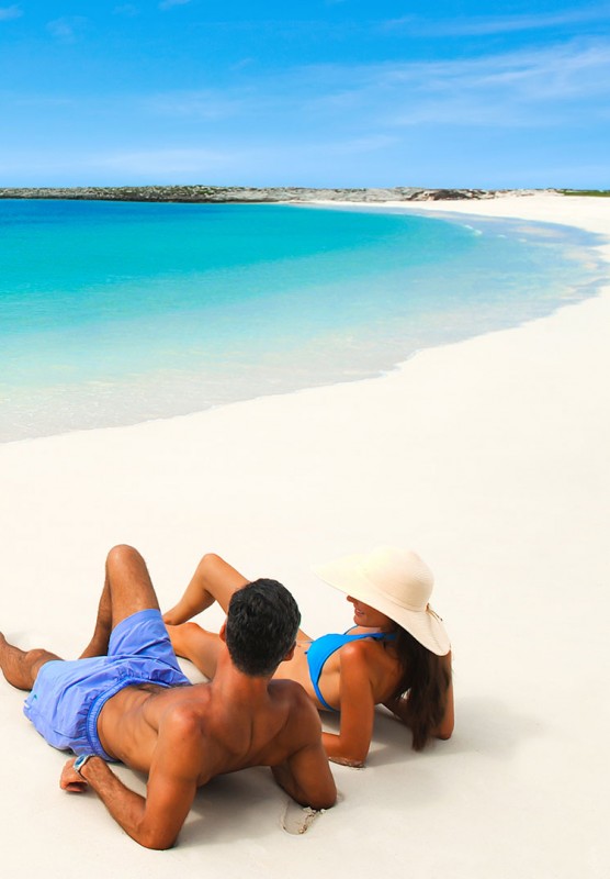A couple lounge together in the sun on a Nassau Paradise Island beach