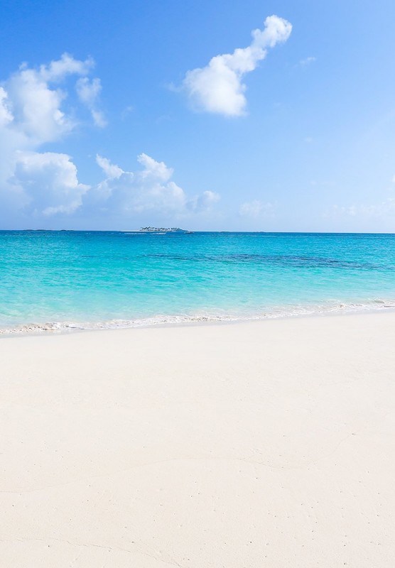 Sandy beach with blue water and boat in the ocean