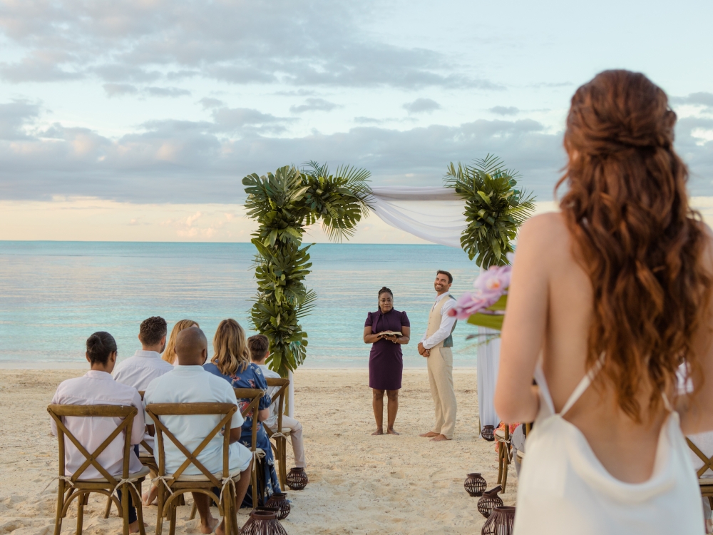 bride walking down the aisle towards groom at a beach wdding