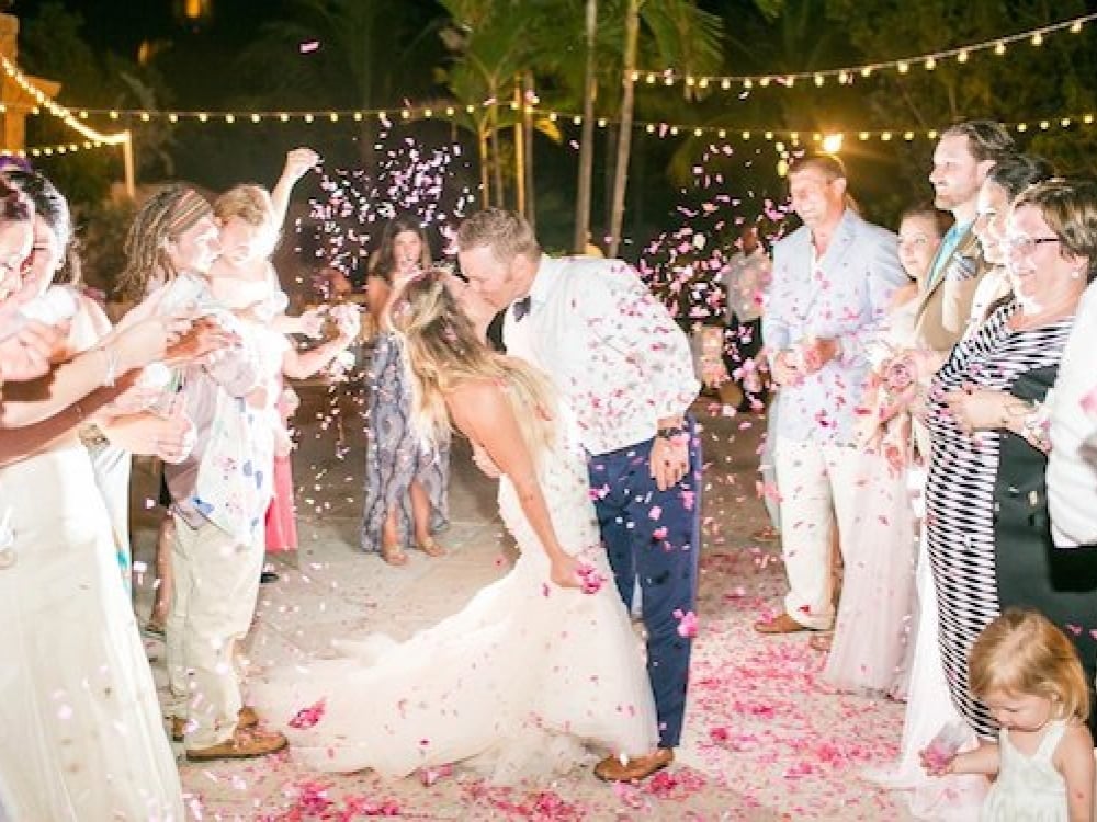 Newlyweds embrace surrounded by loved ones at their Atlantis wedding in the Bahamas