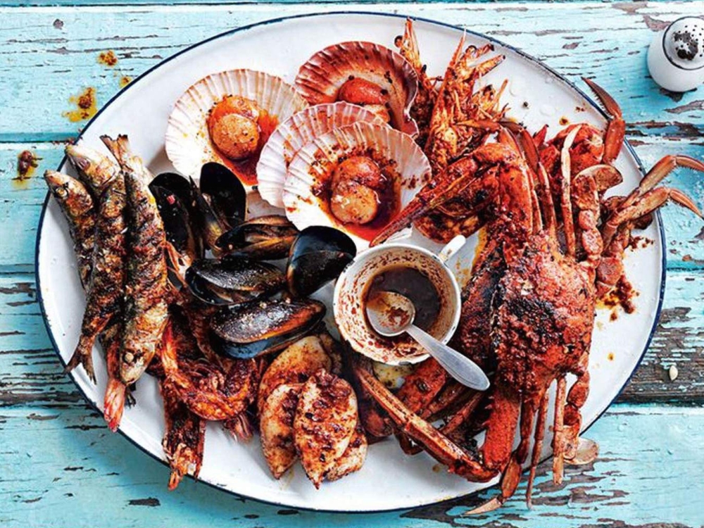 A dish plated with various fresh seafood on a blue table.