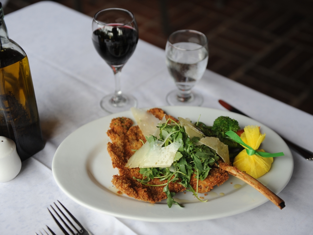 A plate of European-inspired food and glass of red wine. 