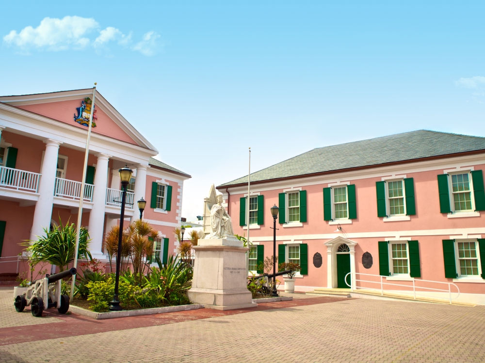 Two grand pink buildings and a public square with a statue of Queen Victoria.