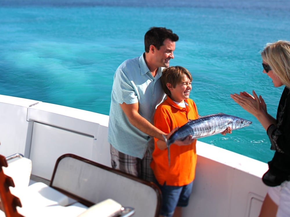 Man and woman and little boy holding a fish on a boat