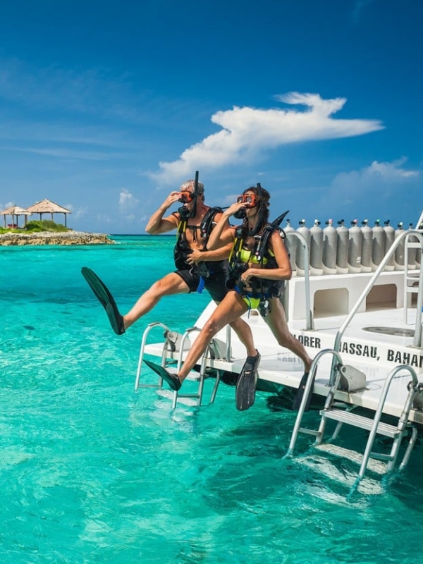 A couple jumping into the water to snorkel from a boat